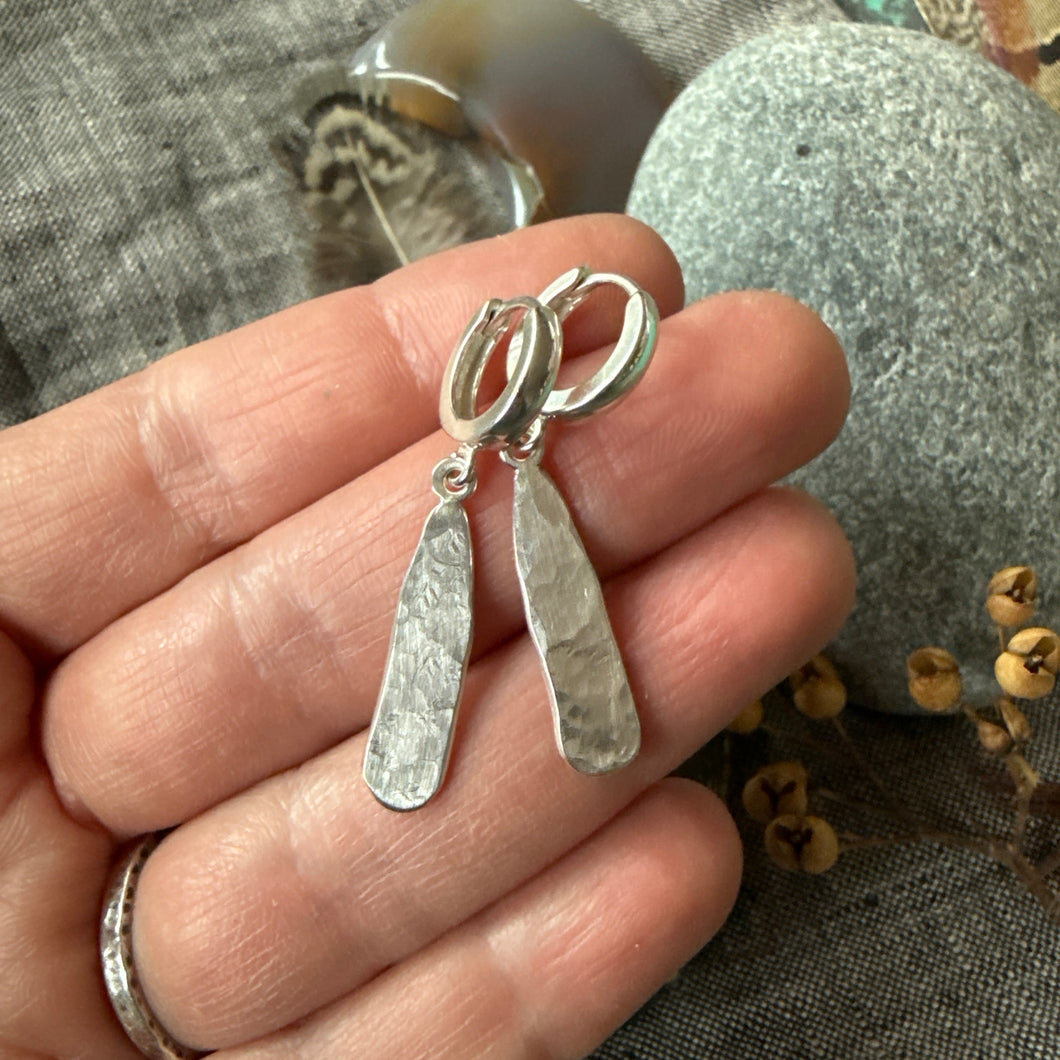 Silver earrings held on a hand 