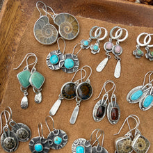 Collection of silver and turquoise earrings on a wooden surface