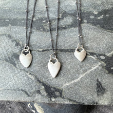 Three silver necklaces on a textured gray surface