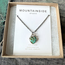 Necklace with turquoise pendant in a 'Mountainside Studio' box on a textured fabric background